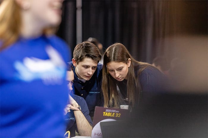Students work around a laptop during the ERPsim competition.