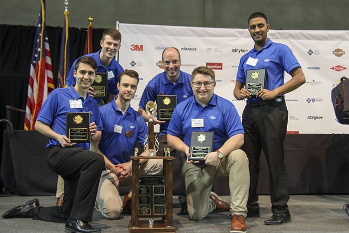 One of the winning teams from the ERPsim competition holds their awards on stage.