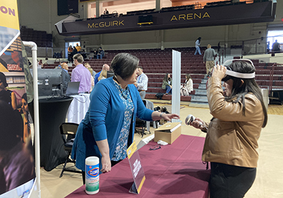 Student is at a tabling event where a staff member shows them how CMU used virtual reality to practice speaking in front of a group.
