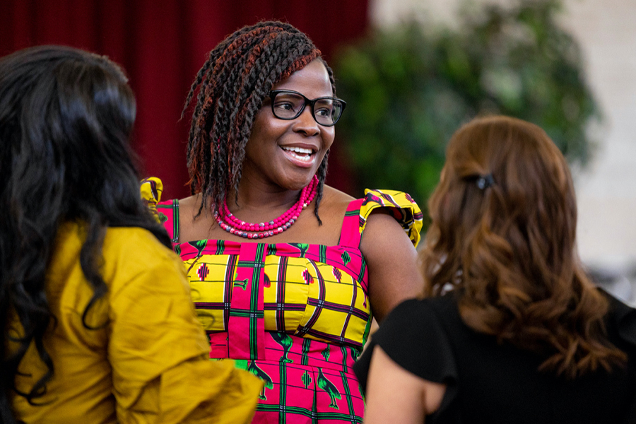 Dr. Kechi smiling, wearing a colorful dress with black framed glasses.