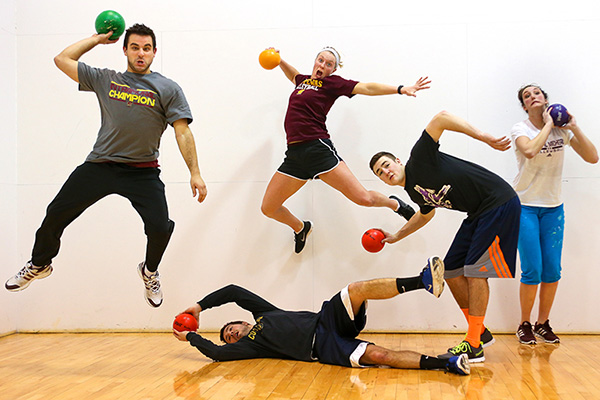 5 students in athletic wear with sports balls in their hands, jumping and playing.