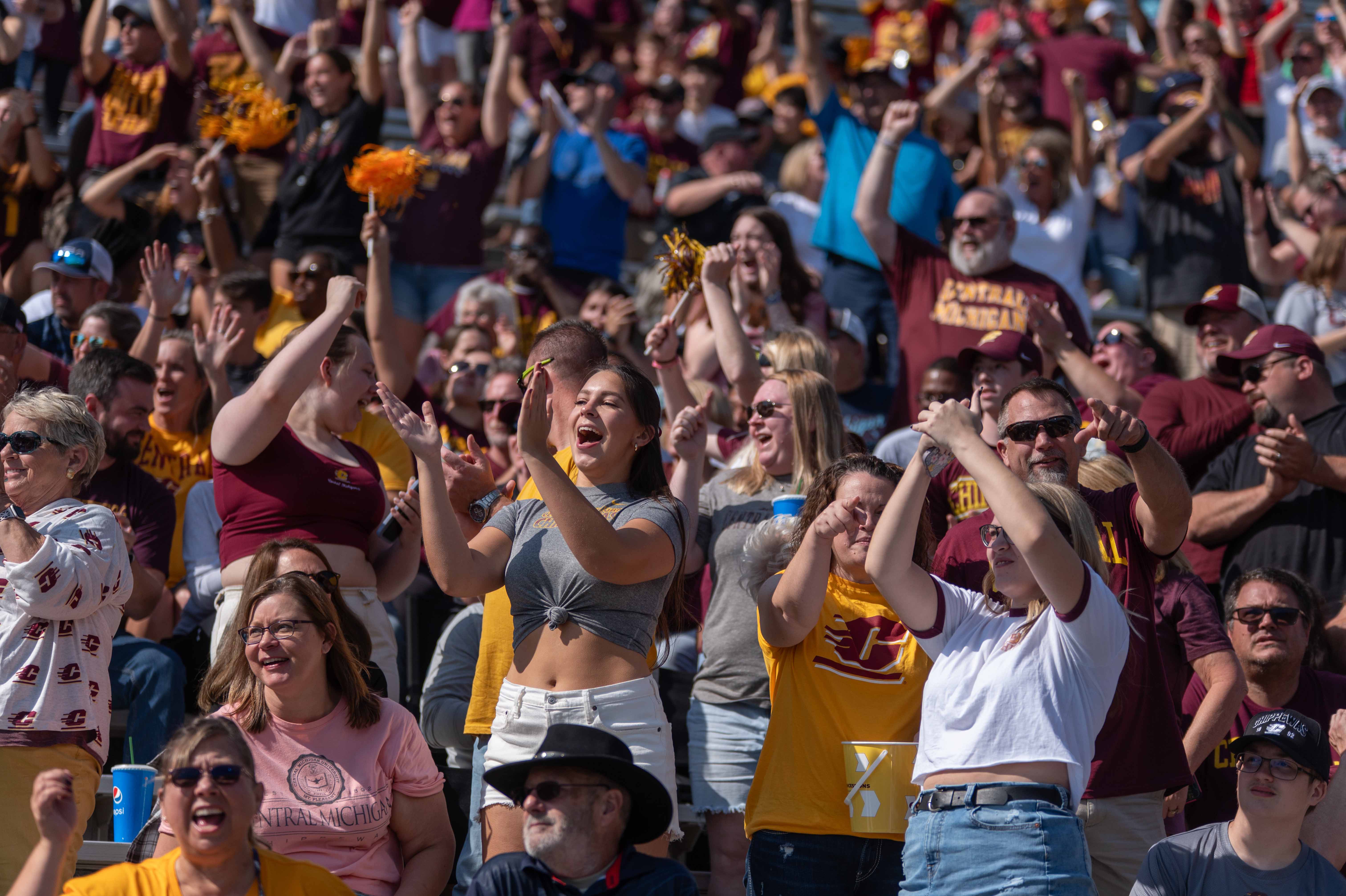 CMU fans wearing maroon and gold cheering on the football team