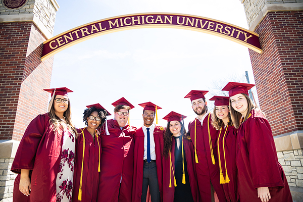 A group of graduating students standing under the Central Michigan University arch