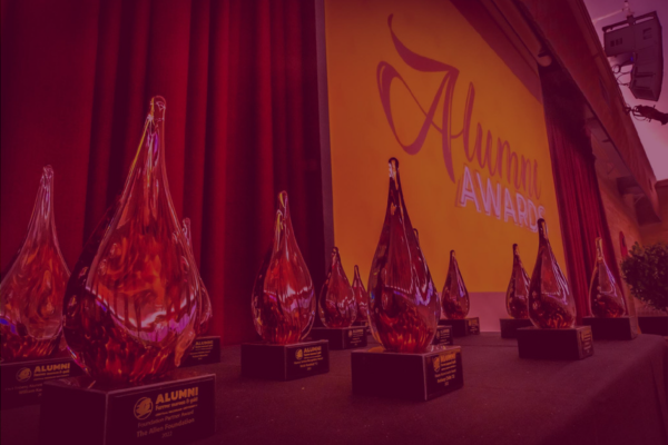 Alumni award statues in a row with a maroon overlay.