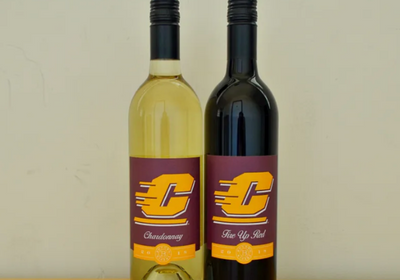 A white and red bottle of wine with the CMU Action C printing on the label.