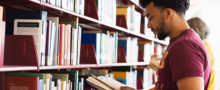 Student browsing through books in stacks