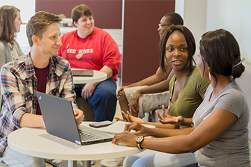 Six students in groups of three having a discussion in the Copeland Suite study room in the Central Michigan University Park Library.