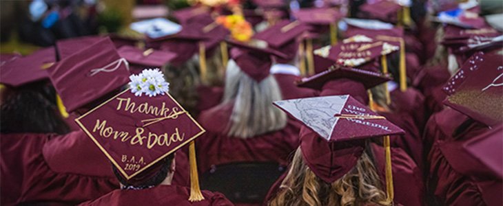 Still image from the backside of a CMU graduation depicting various decor on caps