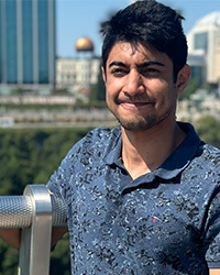 Still photo of Riteesh Mahalinga Mandi in a blue polo against a city scape