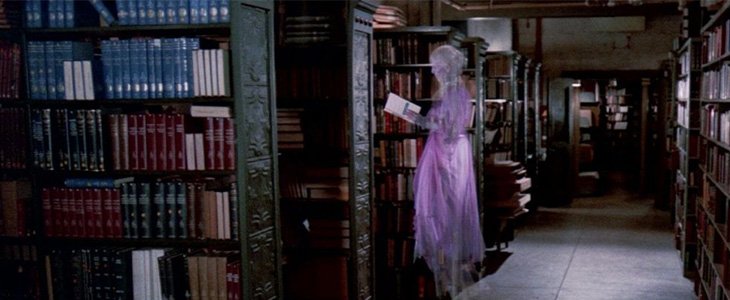 Image of female ghost in pink dress reading a book in the library stacks