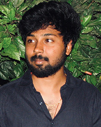 Headshot of Manikar Reddy Boilla in a black shirt against a green leafy background.