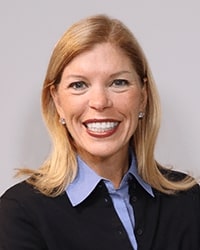 Anne Hornak wearing a black shirt and smiling while posing for a professional headshot.
