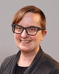 Heather Trommer-Beardslee wearing a gray shirt and smiling while posing for a professional headshot.