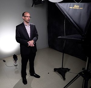 An individual is pictured in the CIS studio while recording with a teleprompter.