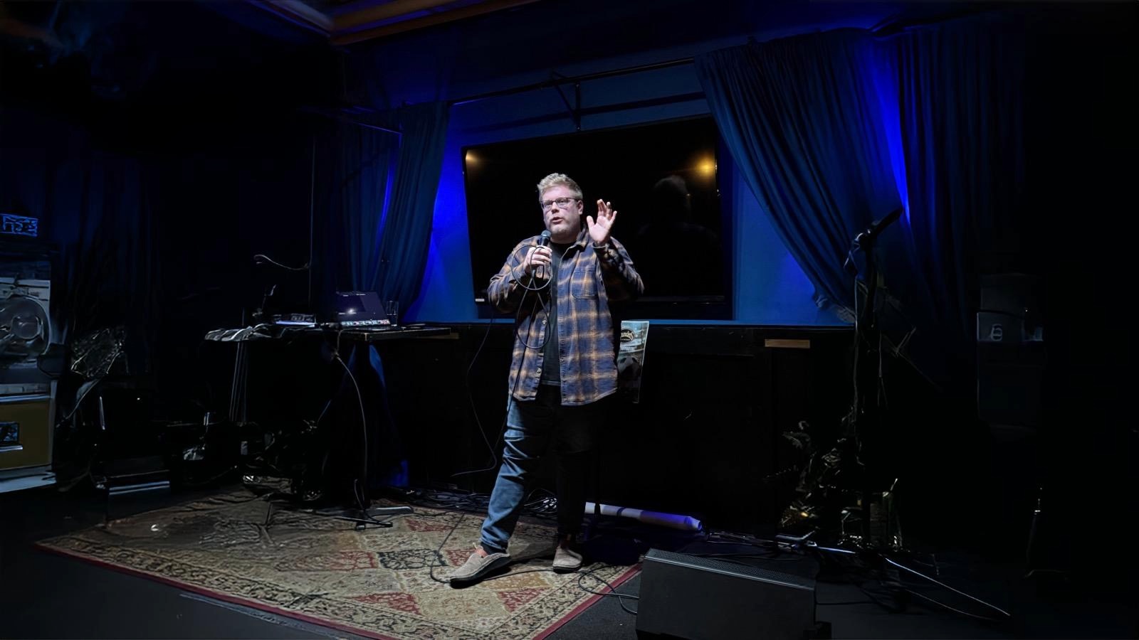 A man holding a microphone in front of a stage.