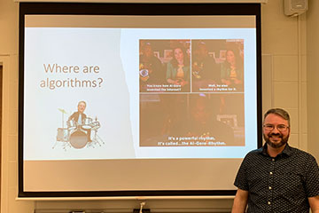 a man standing in front of a projector screen.