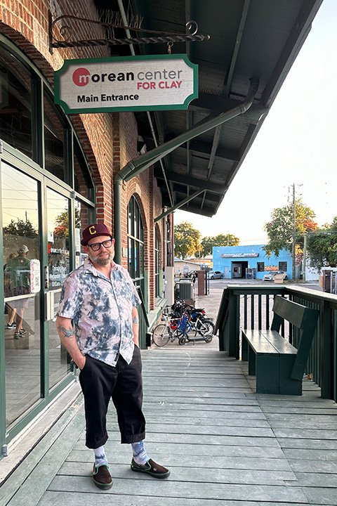 A man standing on a porch at the main entrance of Morean Center for clay