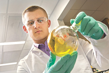 Biomedical student holding a beaker in the lab.