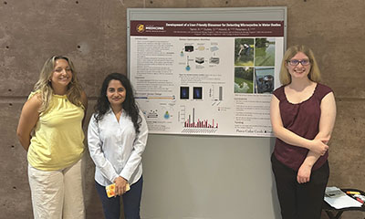 A group of women standing next to a research poster.