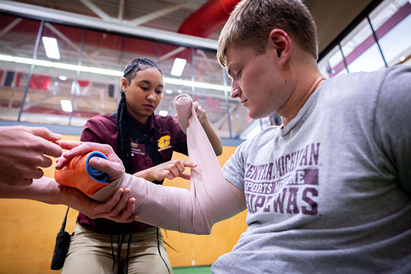 Student Bandaging injured mans arm