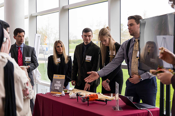 Four students at a table discussing the Drone Lab with New Venture Challenge guests.