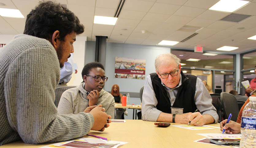 Two students working with a faculty member in a classroom.