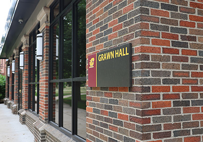 A skewed angle of Grawn Hall's mall entryway. A plaque reading Grawn Hall is centered in the image.