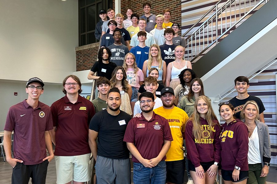 Members of the College of Business's Business Residential Program pose on the grand staircase in Grawn Hall. They are casually dressed in springtime clothes, smiling and looking directly into the camera.