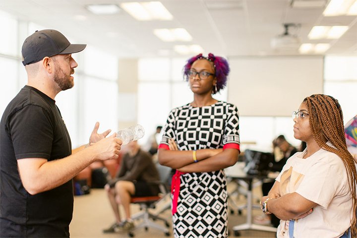 Two female CMU students, Deja Granger and Riley Robinson, speaking to a CMU alum Dan Ward at the Detroit Youthtank.