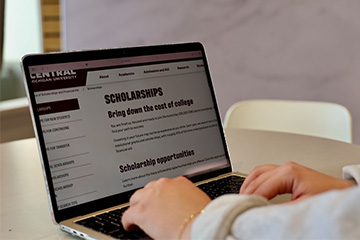 A student accesses scholarship information on a laptop.