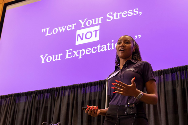 A student standing in front of a purple screen pitching at the 2022 New Venture Challenge.