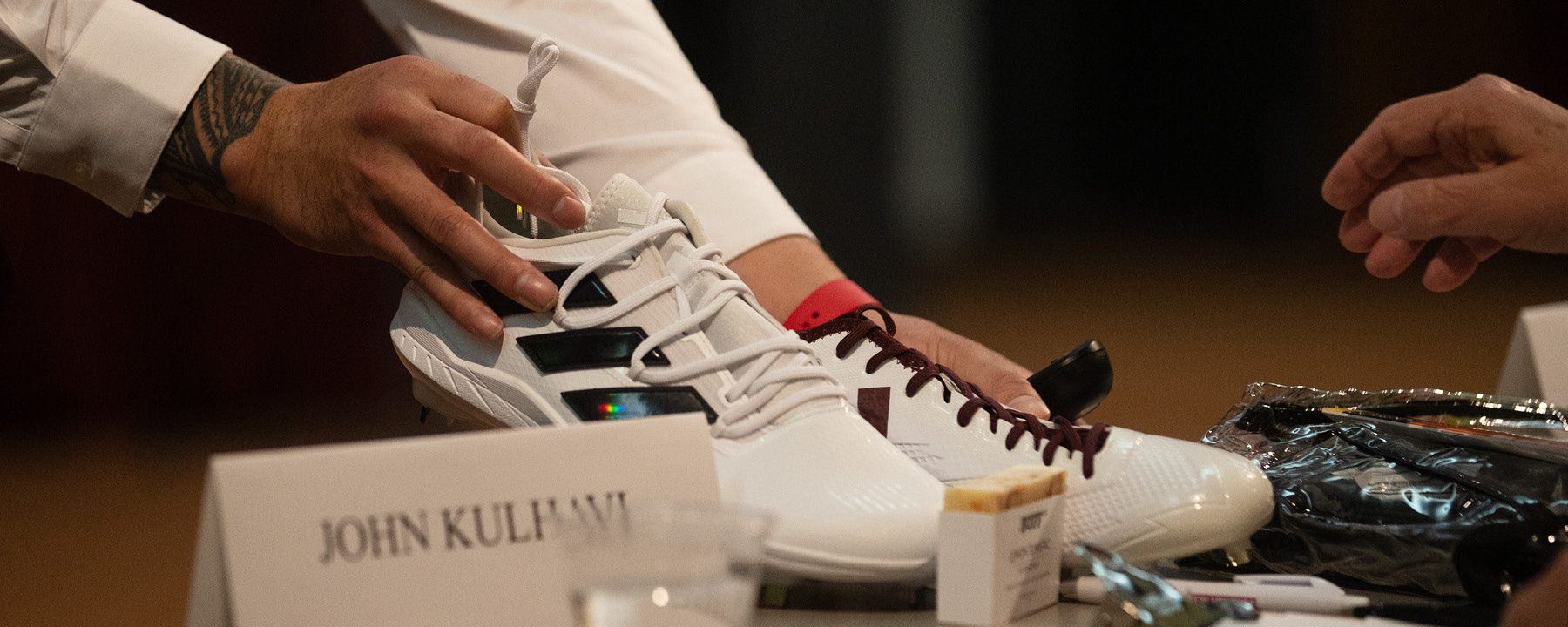 A close up of a student showing a judge two football cleats at the 2024 New Venture Challenge.