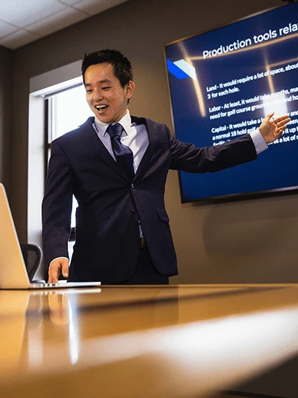 a man in a suit standing in front of a laptop