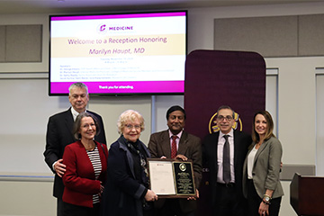 A group of six men and women displaying a large plaque and smiling at the camera.