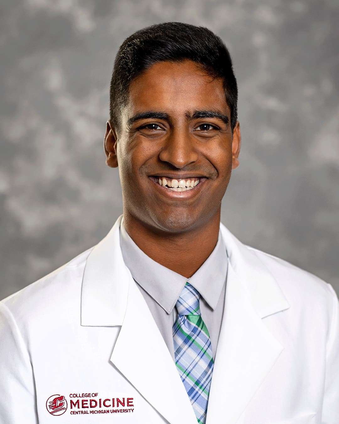 Peddiboyina, Manas 200 x 250 web A male CMU College of Medicine medical student wearing a blue and green plaid tie and his white coat as he smiles for the camera.