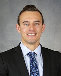 A professional headshot of Miroslav Predny in dark attire against a gray background.