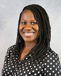 Headshot of Rebecca Dimanche wearing a black blouse with white polka dots.