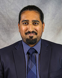 Headshot of Clinton Dsouza wearing a dark gray suit.