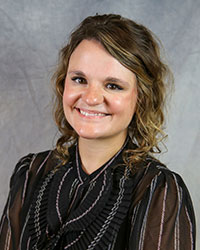 Headshot of Jade Foldie-Schuchardt wearing a black blouse with white stripes.