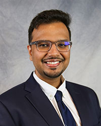 Headshot of Dhruv Verma wearing a dark gray suit.