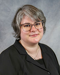 Headshot of Alia Bapary wearing a black suit with a black top.