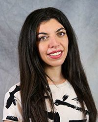 Headshot of Olivia Lossia wearing a white top with a black pattern.