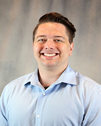 Headshot for Garrett Mason wearing a blue button up shirt.