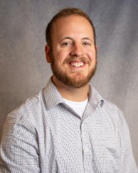 A man with a beard and white button down shirt.