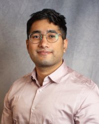 A man wearing glasses and a pink shirt.