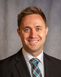 Prybilla, Christopher Christopher Prybilla is wearing a black blazer, white shirt, and patterned tie.