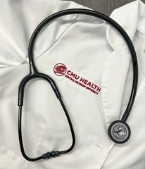 Image of white CMU Health coat with a stethoscope on top around the logo.