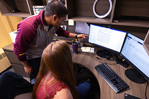 Two researchers working together at a computer in an office environment, illustrating collaboration and academic effort.