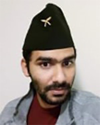 Arjun Poudel with a beard and mustache wearing a black hat, maroon shirt and gray jacket.