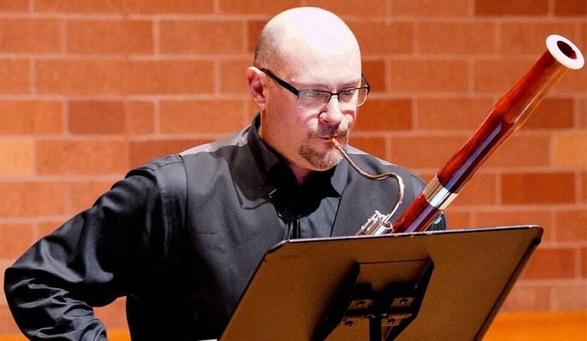 A picture of Dr. Jefferson Campbell in black attire playing bassoon.